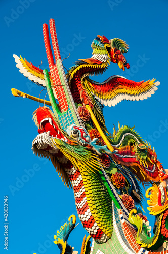 Incredible colorful Chinese figurines of Dragon and Phoenix, one on top of the other lit by sun light in contrast to the super blue sky. Tourist spot on the island of Ishigaki.