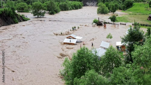 Aerial view of a Flood and flooded houses. Natural disaster and destruction. Fast flowing raging river after strong rain.