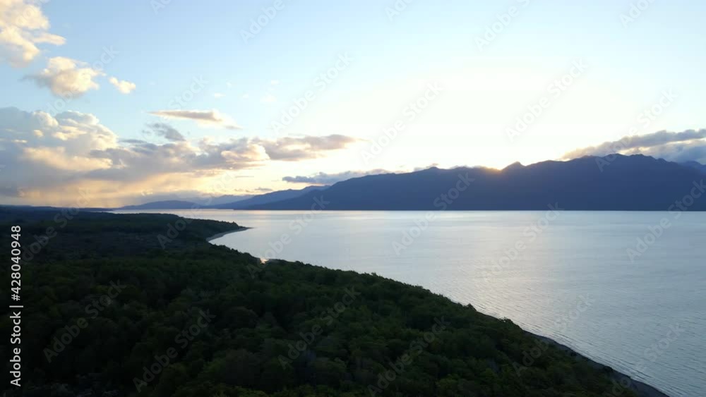 Slow aerial slider view of vast blue lake surrounded by mountains and forest Slow aerial slider view of vast blue lake surrounded by mountains and forest