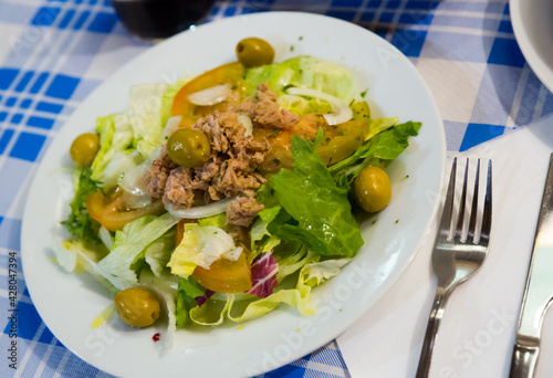 Fresh green salad (Ensalada manchega) with canned fish, thin sliced onion, tomatoes and green olives