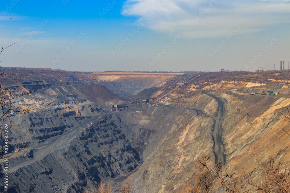 Huge iron ore quarry with working dump trucks and excavators Huge iron ore quarry with working dump trucks and excavators