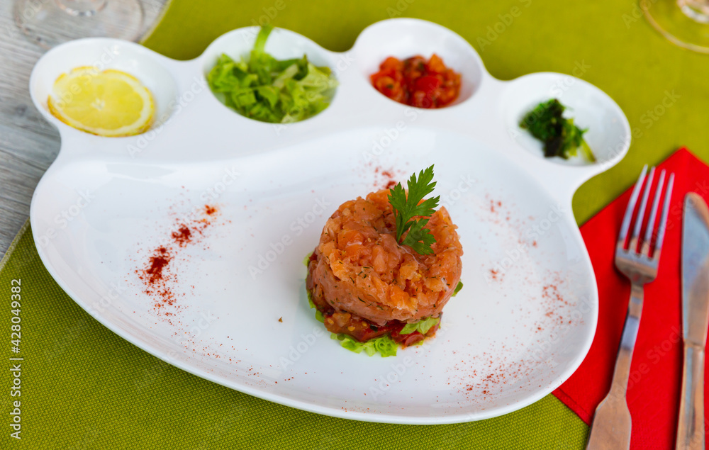 Plate of delicious salmon tartar with lemon and greens