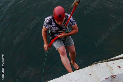 Rope jumping from high altitude of bridge. Bungee jumping from pedestrian bridge over beautiful river