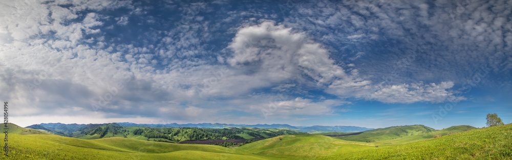 Panoramic view of green hills and picturesque blue sky with white clouds