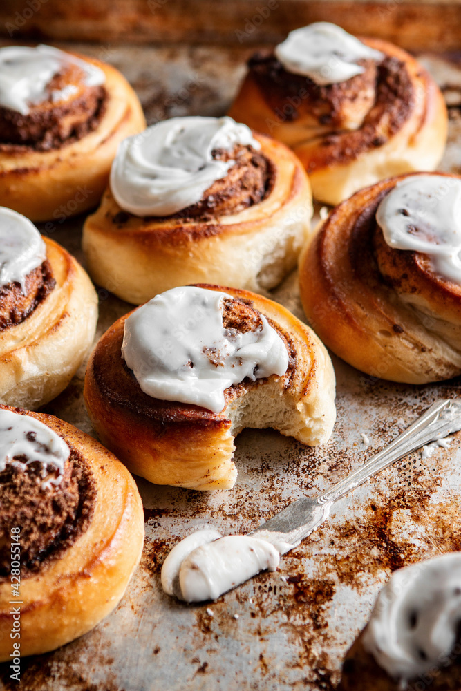 Baked Cinnamon rolls with frosting on a baking tray Baked Cinnamon rolls with frosting on a baking tray