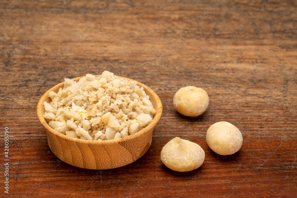 macadamia nut flour in wooden bowl against rustic weathered wood, gluten-free starch substitute macadamia nut flour in wooden bowl against rustic weathered wood, gluten-free starch substitute