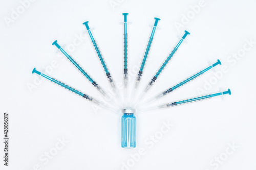 Vaccination. Medical syringe and ampoule on blue background. Disposable syringe and injection vial. Diabetes insulin injection syringe. Human hand holding vial with vaccine against corona virus.