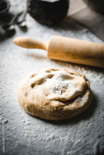 Dough and rolling pin on the table cloth in the moody light