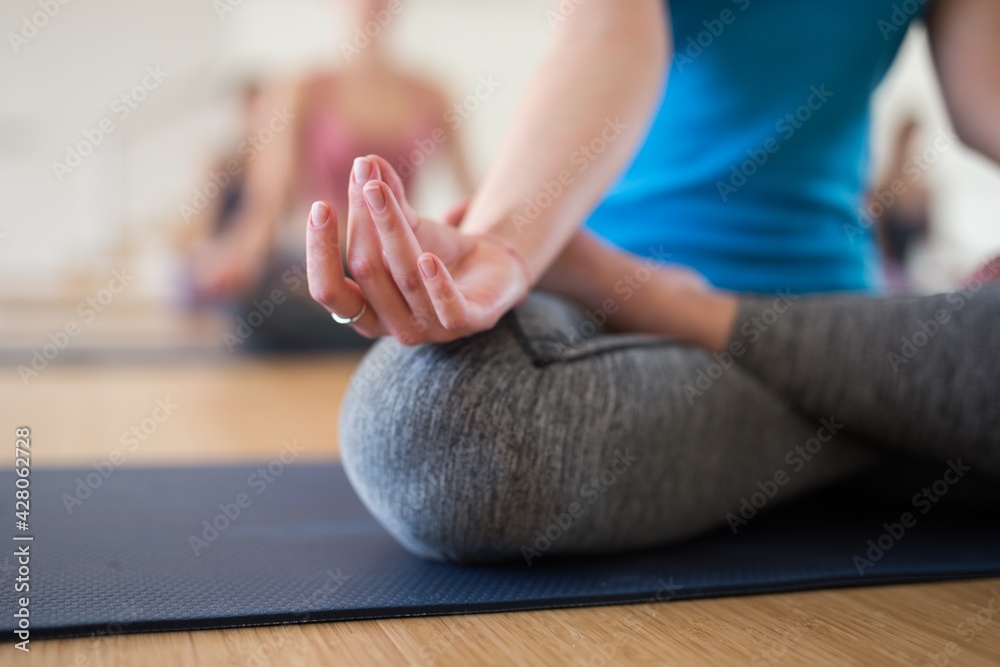 Closeup of female hand with fingers folded in mudra. Hand lying on knee while woman sitting in yoga position Padmasana.