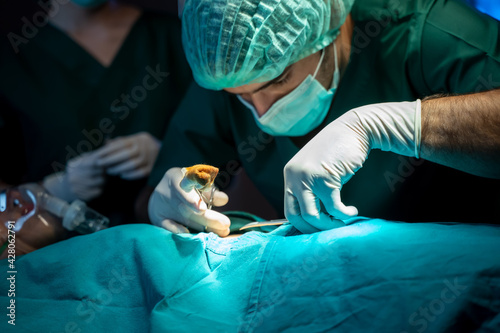 Team of professional surgeons and nurses suture wound after successful surgery in surgery room. photo