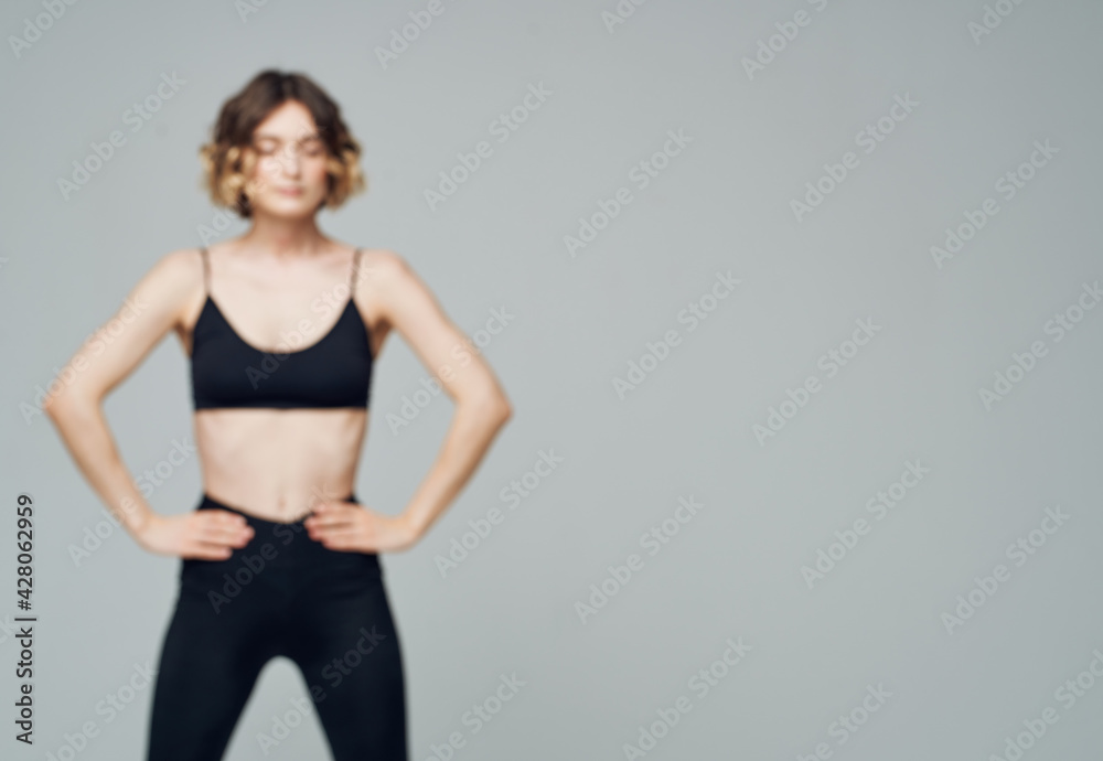 Women in sportswear are engaged in fitness on a gray background in leggings cropped view Women in sportswear are engaged in fitness on a gray background in leggings cropped view