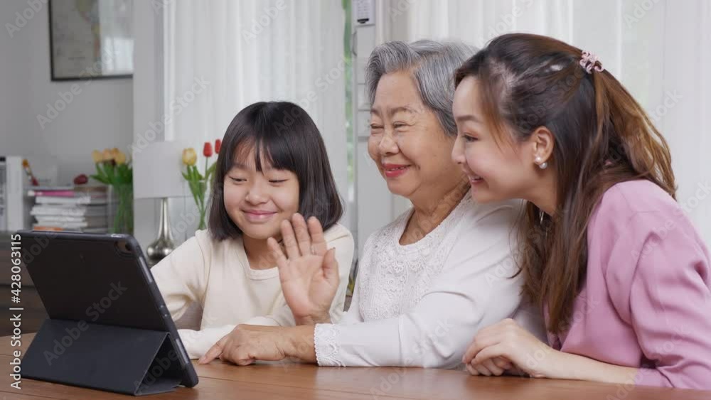 Asian people using video call together at living room. They looking tablet and talking together. Asian people using video call together at living room. They looking tablet and talking together.