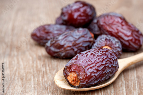 Close-up Medjool dates or dates fruit in wooden spoon on table, This fruit is highly nutritious and is commonly eaten during fasting or Ramadan.