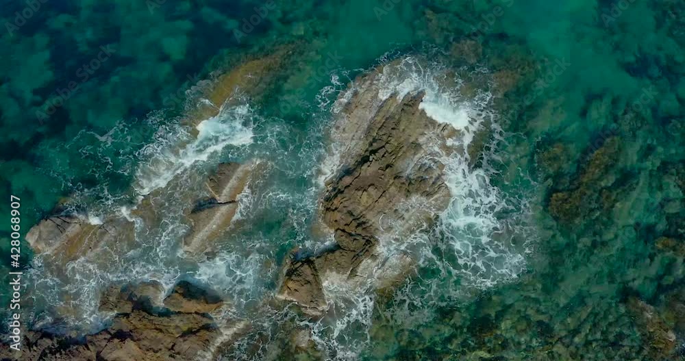 Crystal Clear Blue Sea Waves Splashing On Rocky Outcrops. Cavalleria Beach In Menorca, Spain On A Sunny Summer Day. aerial static