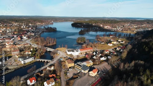 Aerial flyover rural city with natural blue lake during golden sunny day. Bengtsfors, Sweden. photo