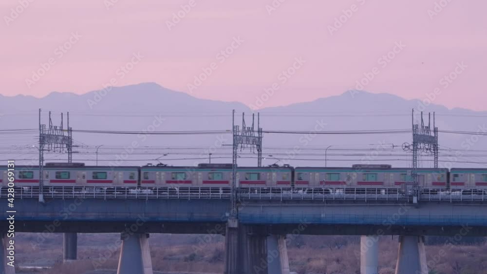 Train Passing By On Railway Bridge At Dusk In Tokyo Japan With Majestic Mountain In Background. wide shot Train Passing By On Railway Bridge At Dusk In Tokyo Japan With Majestic Mountain In Background. wide shot