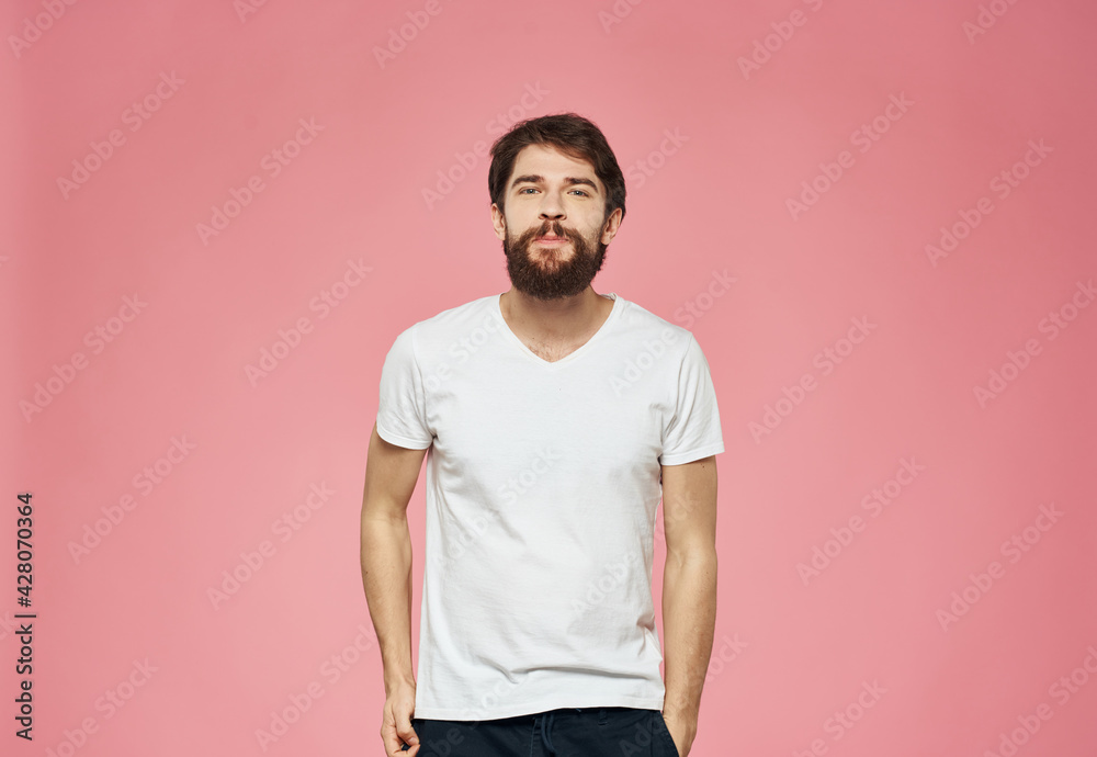 A guy with a beard on a pink background, a white T-shirt and dark trousers A guy with a beard on a pink background, a white T-shirt and dark trousers