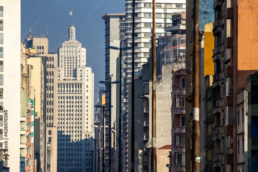 Row of residential and office buildings seen in perspective with public streetlights with Altino Arantes building in the background, in downtown Sao Paulo, Brazil