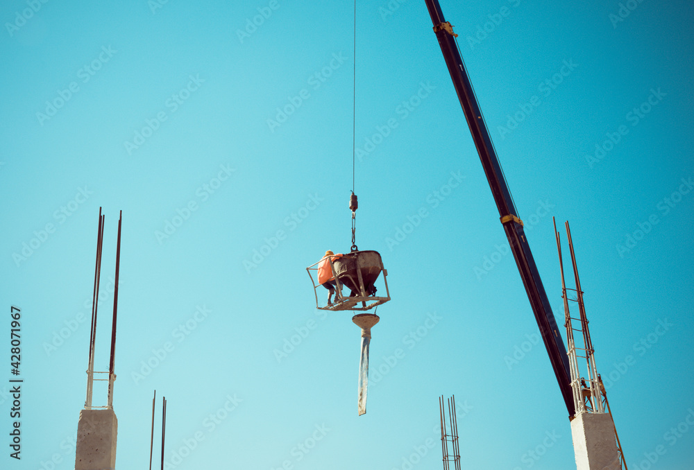 Worker pouring concrete by crane at construction site. Worker pouring concrete by crane at construction site.