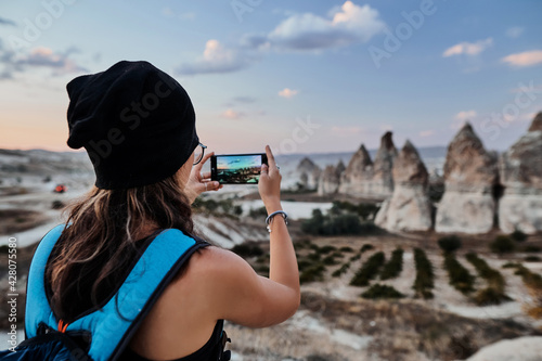 Obraz na płótnie Beautiful tourist woman taking picture of Stone houses on her smartphone in Love valley in Goreme village. w salonie