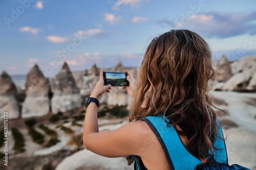 Obraz na płótnie Beautiful tourist woman taking picture of Stone houses on her smartphone in Love valley in Goreme village. w salonie