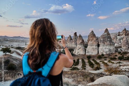 Obraz na płótnie Beautiful tourist woman taking picture of Stone houses on her smartphone in Love valley in Goreme village. w salonie
