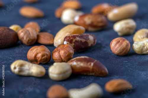 Assortment of various types of nuts on dark background. Cashew, hazelnuts, almonds and Brazil nuts close up. Healthy vegetarian snacks. Protein-containing food. Selective focus.