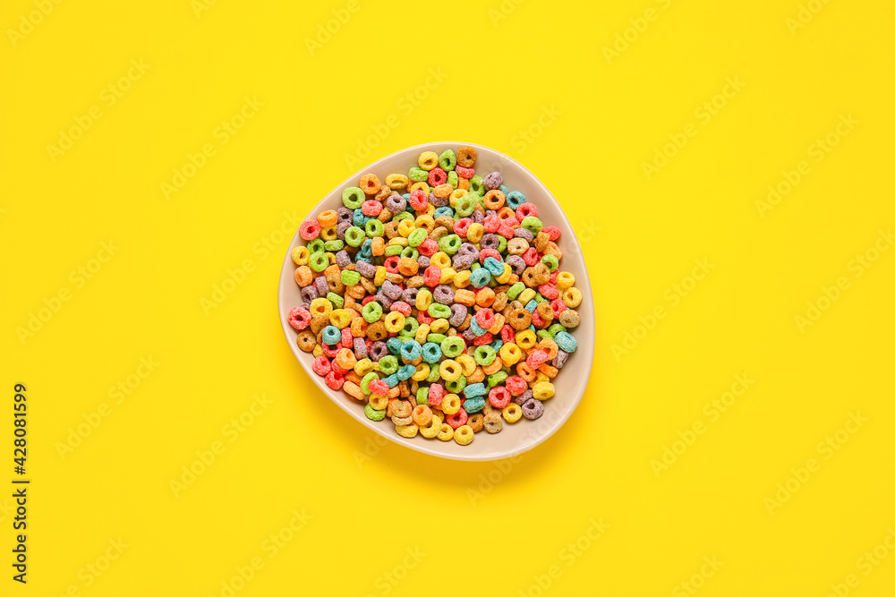 Bowl with tasty cereal rings on color background