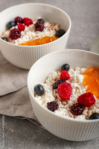 Bowls of cottage cheese with berries and fruit jam on grunge background