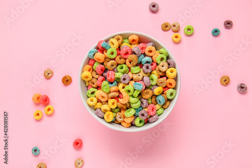 Bowl with tasty cereal rings on color background