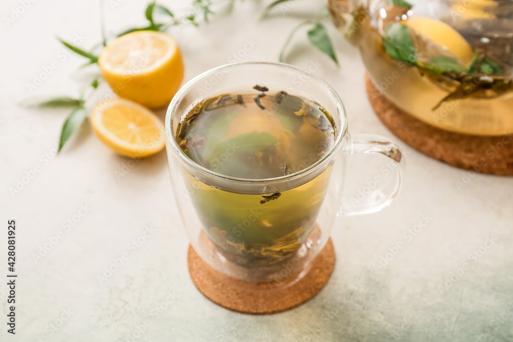 Cup of hot green tea with lemon on light background Cup of hot green tea with lemon on light background