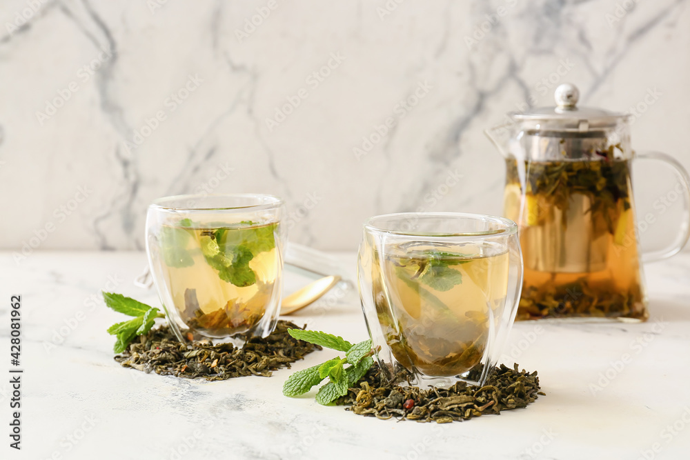 Fototapeta premium Cups of hot green tea on light background