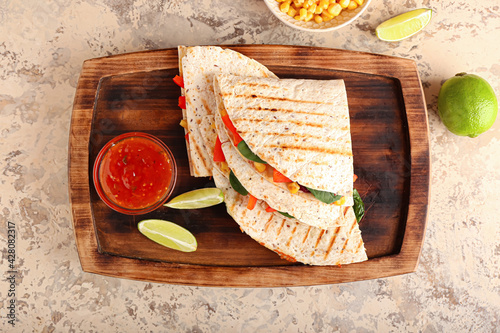 Tray with tasty vegetarian quesadillas, lime and sauce on light background