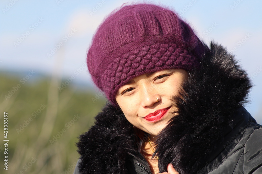 Beautiful girl is wearing thick black color clothe with dark pink cap on blur background at Nepal Beautiful girl is wearing thick black color clothe with dark pink cap on blur background at Nepal