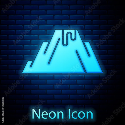 Glowing neon Volcano eruption with lava icon isolated on brick wall background. Vector