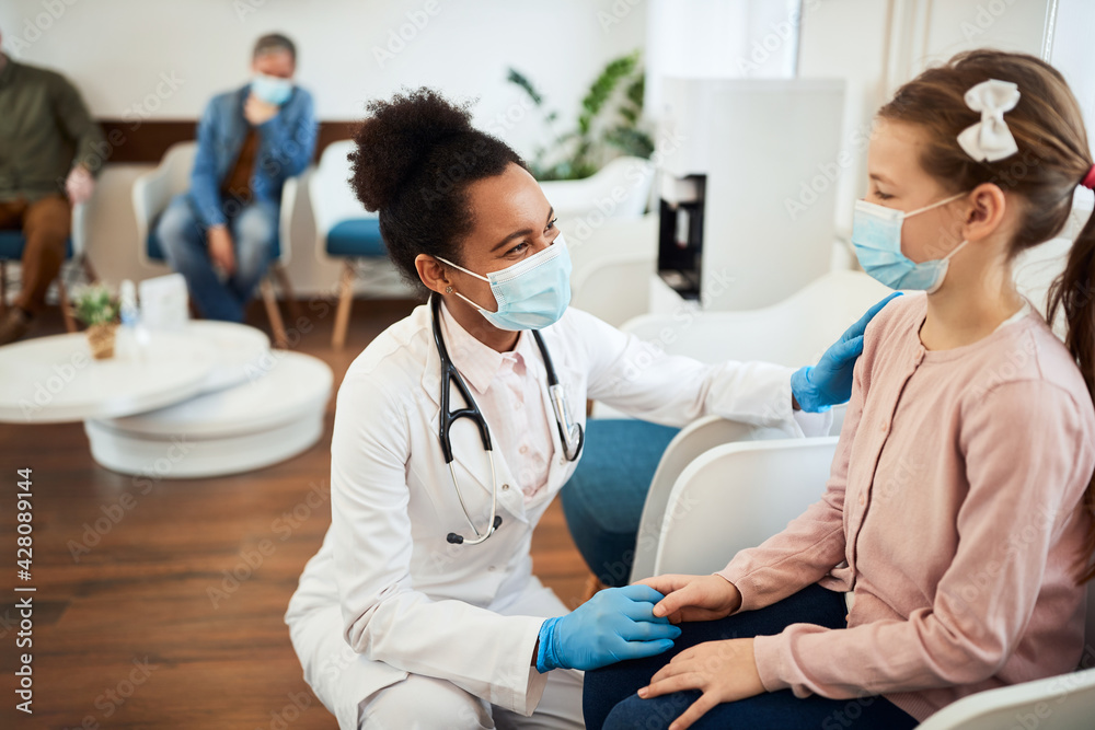 Happy African American dentist talking with small girl in waiting room at dental clinic. Happy African American dentist talking with small girl in waiting room at dental clinic.