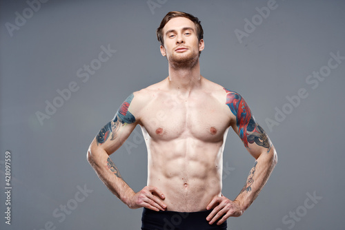 athletic man with pumped up abs tattoos on his arms