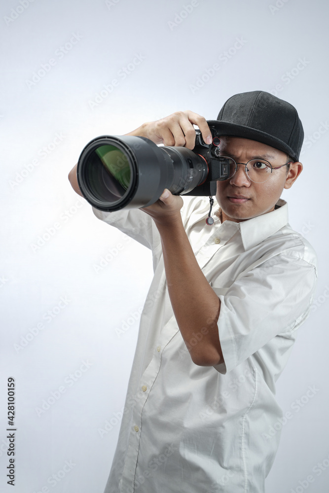 The photographer looks through the viewfinder while shooting with the professional camera isolated in white background. The photographer looks through the viewfinder while shooting with the professional camera isolated in white background.