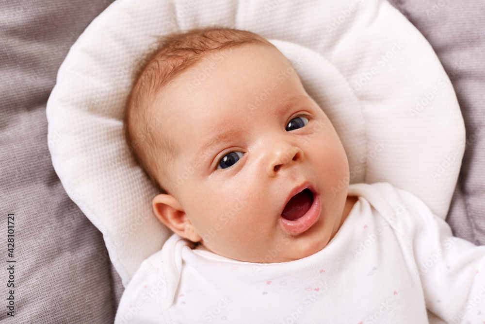 Cute happy little on gray blanket looking at camera, keeping mouth opened, wearing white clothing, adorable infant girl studying world around. Cute happy little on gray blanket looking at camera, keeping mouth opened, wearing white clothing, adorable infant girl studying world around.