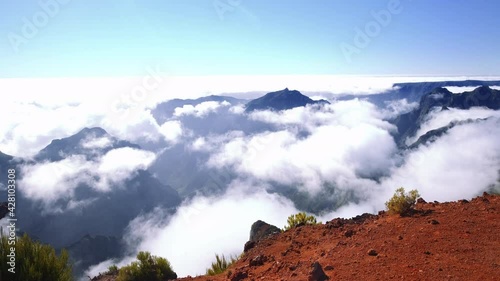 Pov walk on top of Pico do Arierio with breathtaking view down the mountain during sunny day. Clouds hovering in the air. Madeira,Portugal photo