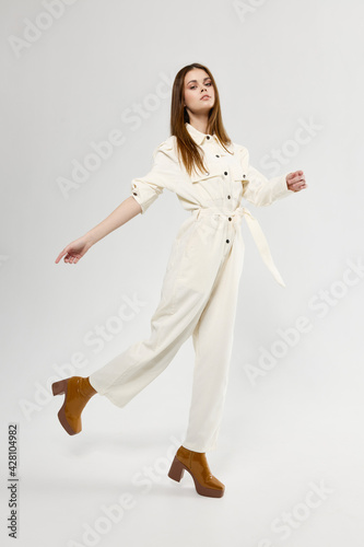 woman in a fashionable jumpsuit and boots with heels on a light background in full growth © SHOTPRIME STUDIO