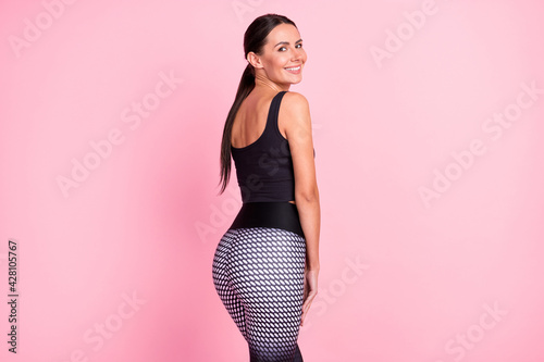 Photo of charming sexy young lady sportswear standing back smiling isolated pink color background