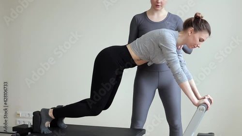 A beautiful teenage girl working out with a pilates instructor at a gym