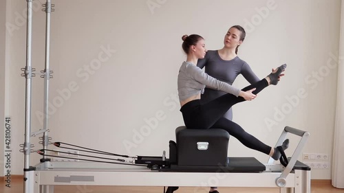A beautiful teenage girl working out with a pilates instructor at a gym