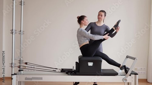 A beautiful teenage girl working out with a pilates instructor at a gym