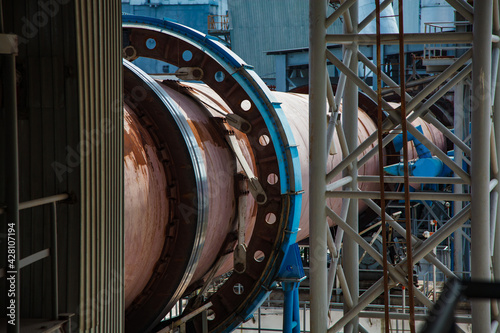 Standard Cement plant. Close up of rotary clinker kiln. Rusted tube and blue gear.
