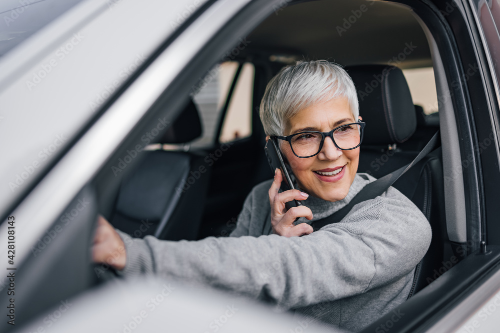 Close-up portrait of an older woman driving a car and talking on smart phone. Close-up portrait of an older woman driving a car and talking on smart phone.