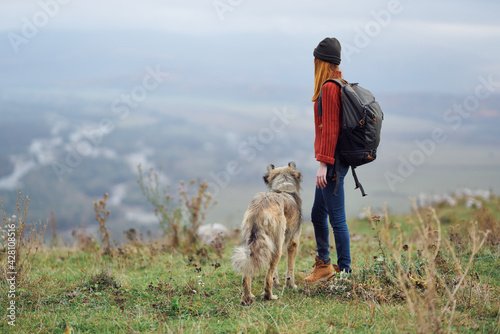 woman hiker with backpack with dog in the mountains travel friendship