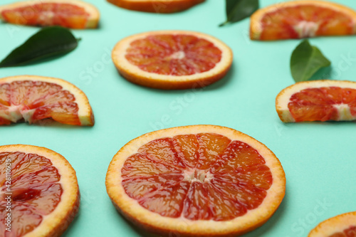 Red orange slices and leaves on mint background