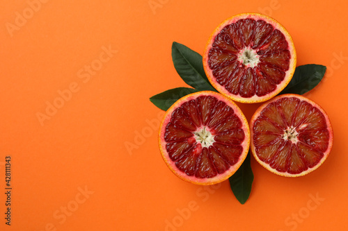 Red orange halves and leaves on orange background